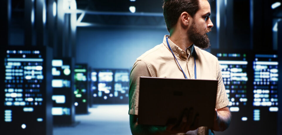 Supervisor using laptop to oversee energy consumption across server hub components and distributors. Serviceman ensuring high tech facility sensors for temperature and humidity are working properly